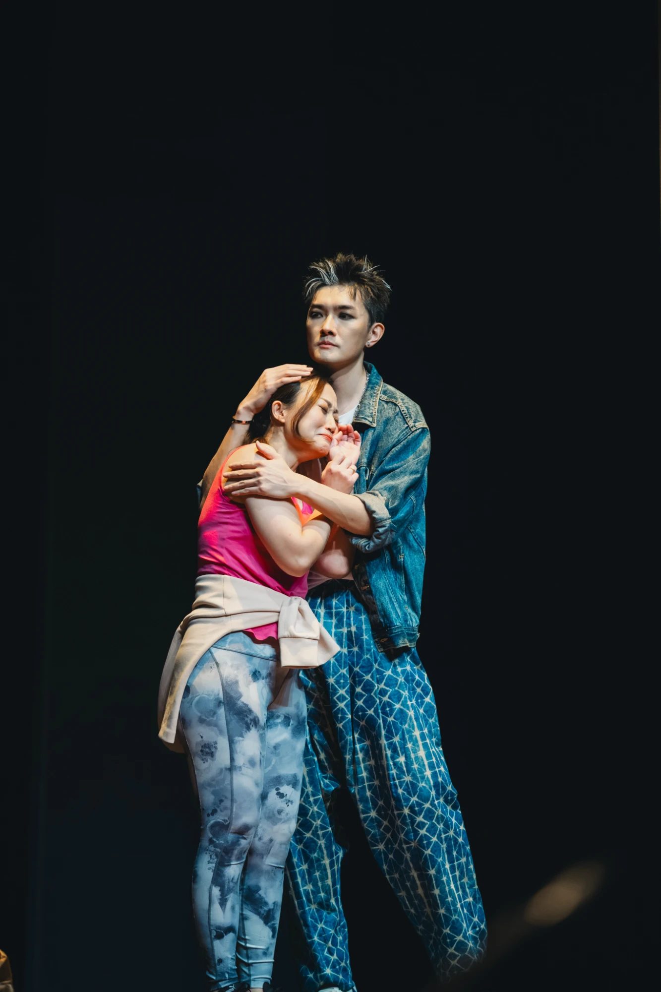 Don Giovanni in a denim jacket, embracing a woman