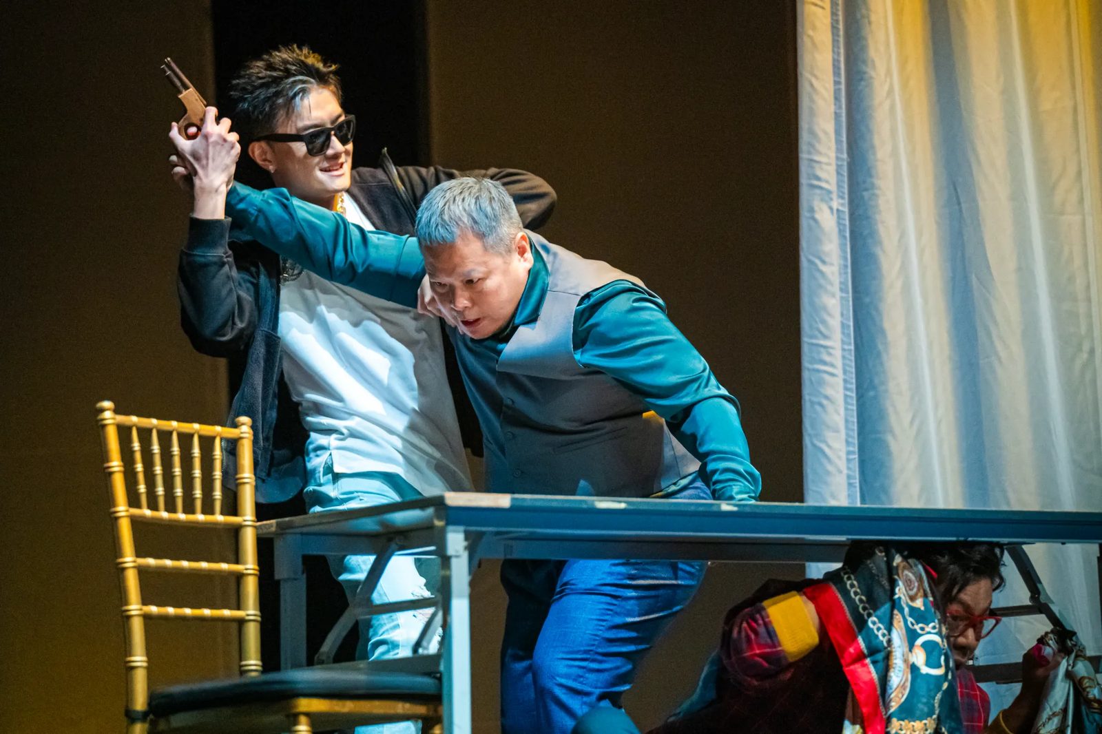 Don Giovanni raising a pistol in a scene at the table